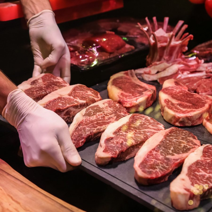 vista-laterale-lo-chef-produce-carne-di-manzo-marmorizzata-cruda-per-bistecche-su-un-supporto_141793-12509